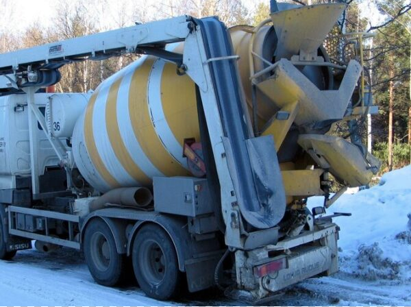 Yellow and white redi mix concrete truck and mixer on snowy roadway